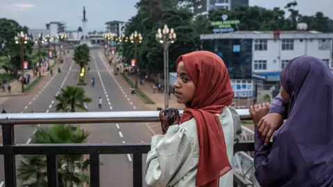 AFP via Getty Images Two young women looking over a bridge on to a newly built roads near a monument in Addis Ababa - May 2026