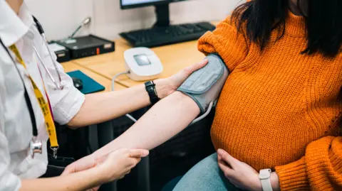 A woman has her blood pressure taken by a doctor