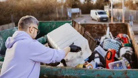 Getty Images Man in purple jumper and gloves uses a tip