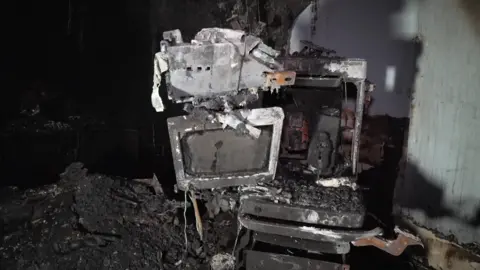 A fire damaged monitor surrounded by ash