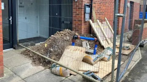Rubble with building with exposed pipes. 
