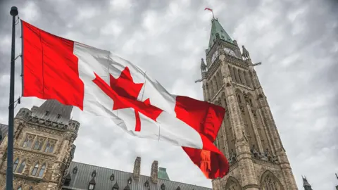 A photo of the Canadian flag flying in front of Parliament Hill in Ottawa, Canada.