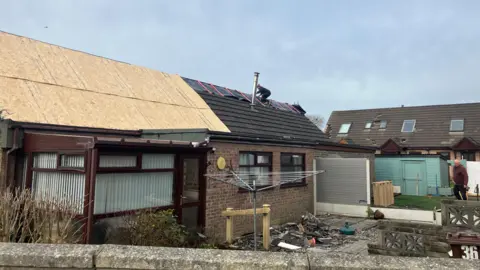 A house with wooden panels covering damaged roofs