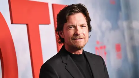 Getty Images Jason Bateman, wearing a black top and black jacket
