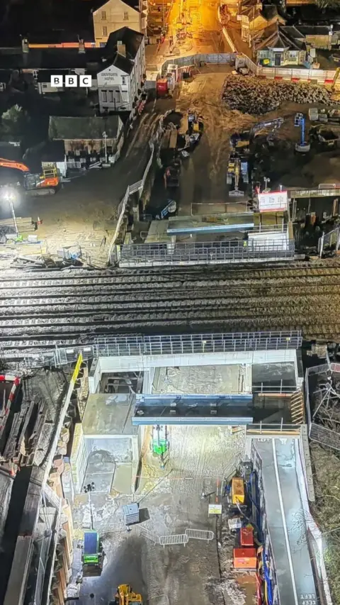 A bridge over a road with roadworks at night.