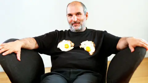 Alan Yentob, pictured wearing a black T-shirt with two fried eggs on it, presenting the arts series imagine