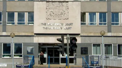 The outside of of Croydon Magistrates Court, a cream and gray building lined with windows, in South London