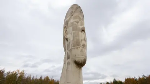 ADAM VAUGHAN/EPA/Shutterstock The Dream sculpture is a 66ft (20m) white sculpture said to resemble the head and neck of a young girl. It towers above nearby trees.