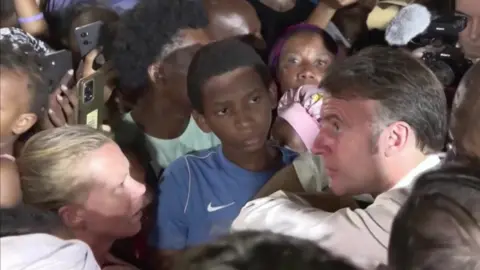 French President Emmanuel Macron during a heated conversation with a woman in a crowd in Mayotte