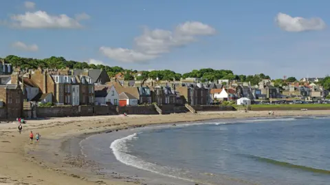 Getty Images An image of west bay beach in North Berwick, a curved expanse of sand lapped by a gentle tide, with a mix of housing ranged along the shore