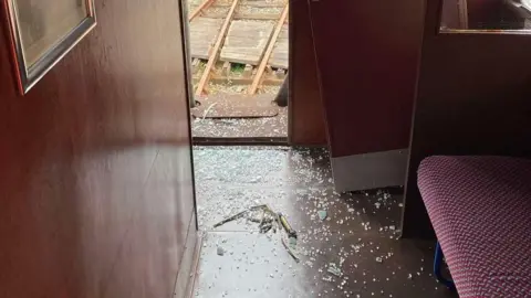 Downpatrick and County Down Railway The inside of a train carriage with broken glass on the floor