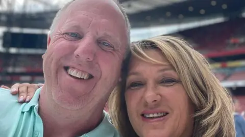 Mark Sullivan A blonde haired woman rests her head against a man wearing a turquoise polo shirt, as both of them smile at the camera.