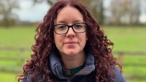 BBC A caput and shoulders changeable of Kayleigh Griffiths opinionated successful her plot looking into camera pinch a neutral expression. She has agelong reddish-brown curlyy hairsbreadth and is wearing a heavy navy jacket. She has achromatic framed glasses.