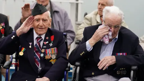 PA D-Day veteran Bernard Morgan (left), 100, from Crewe, salutes as veteran Harry Birdsall, 98, from Wakefield, becomes emotional as he travels on Brittany Ferries' Mont St Michel
