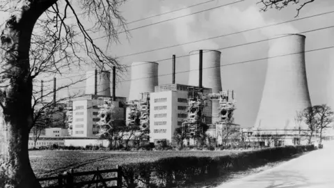 Getty Images A black and white image of the cooling towers at Chapelcross viewed from behind with a tree in the foreground