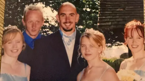 Eugene Scardifield Smartly dress family pose for a photo at a wedding