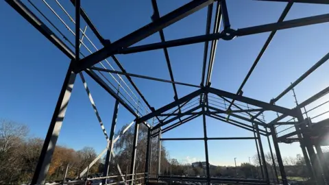 Wiltshire Council Steal beams forming the shell of a building with a blue sky behind