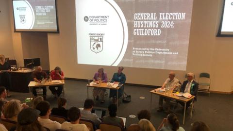 Guildford candidates sitting at tables in Surrey university lecture theatre