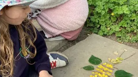 Hannah Lee A girl in pink cap looking at flowers 