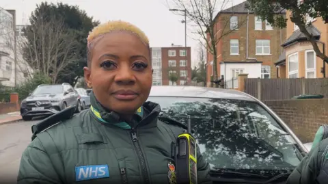 Mental health nurse Clara Mmazhandu in uniform on a London street.