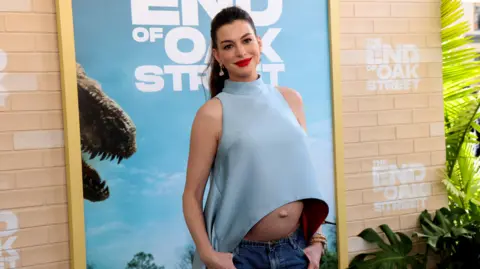 Anne Hathaway wearing a top showing her exposed baby bump on the red carpet at the world premiere for The End of Oak Street in Los Angeles on 9 August