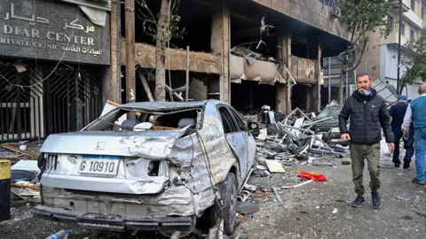 EPA People walk past buildings and cars damaged by an Israeli airstrike in the Mar Elias neighborhood in central Beirut, Lebanon (November 18, 2024)