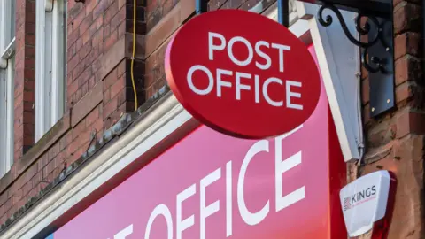 A red circular sign for the post office above a red horizontal sign also for the post office.