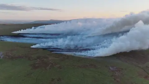 Aerial view of smoke over a wide area of charred moorland