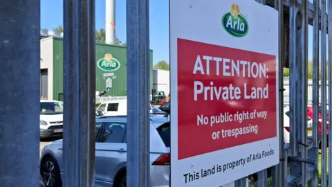'It's a dying town': Community hit hard by factory's loss 10 BBC/Seb Cheer A sign is in the foreground, with the Arla logo at the top. Underneath on the sign, it says "ATTENTION: Private Land. No public right of way or trespassing. This land is property of Arla foods." In the background you can see a building at the Arla site in Settle.