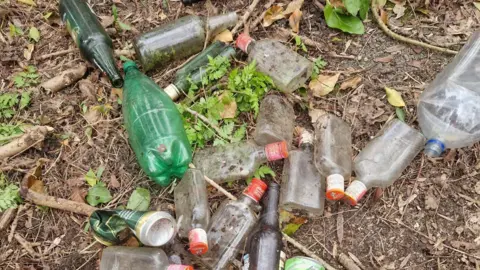 Peterborough Litter Wombles bottles and other rubbish dumped on the ground.