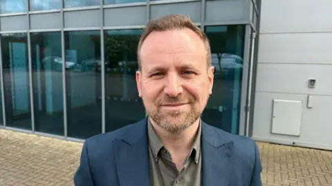 Ben Parker/BBC Gary Jeffreys in a suit standing outside