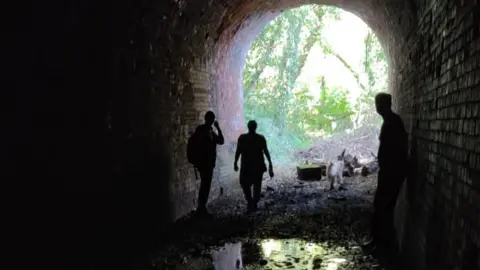 Supplied The silhouettes of three people in a tunnel