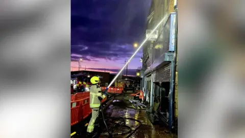 South Yorkshire Fire and Rescue A firefighter aiming a hose at an upper floor window