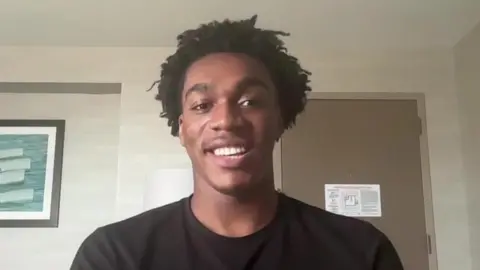 A screen shot of a zoom call with Amari Williams. He had short dark hair and is wearing a dark shirt.