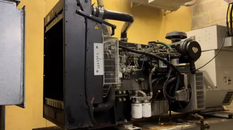 A black generator with silver wires and black and white canisters attached. 