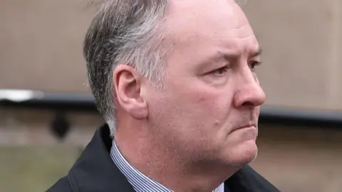 PA Media Ian Paterson - a man with grey hair with a solemn expression on his face.
