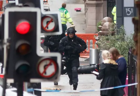 Getty Images An armed police officer runs uphill in an area cordoned off outside the Park Inn hotel