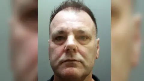 Merseyside Police Image is a police mugshot of Pascal Blasio, a middle aged man with short dark hair and a receding hairline