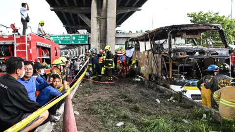 Getty Images Rescue workers and fire fighters stand near the bus