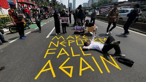 Anindita Pradana/BBC Indonesia Demonstran di depan tanda di jalan yang bertuliskan: "Hancurkan nepotisme lagi".