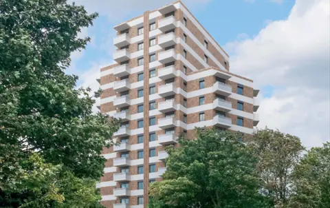Ealing Council CGI shows tall tower block with white balconies and light brick behind trees on a bridge