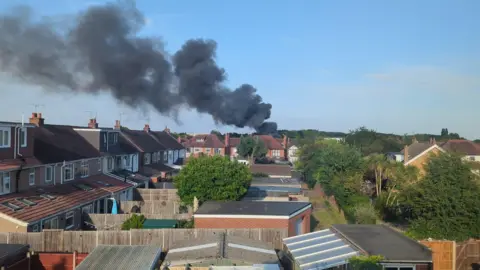 A large plume of smoke above numerous back gardens.