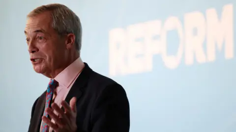 Reform UK leader Nigel Farage speaking, standing in front of blue wall with white 'Reform' text written on it