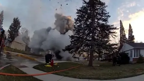 A large plume of smoke emanates from a suburban road in an explosion.