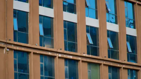 Thanyarat Doksone/ BBC A row of windows with bars on the inside 