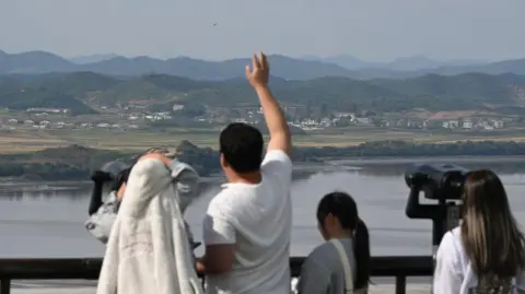 Getty Images Visitors use binoculars to look at the North Korean side of the Demilitarized Zone (DMZ) that separates the two Koreas from South Korea's Odusan Association Observatory in Paju on October 9, 2024. 