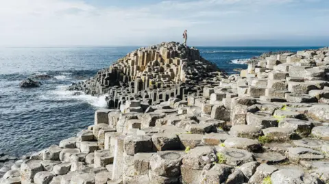 Getty Images A stock image of the Giant's Causeway on Northern Ireland's north coast. It is lots of hexagonal rocks placed together beside the sea front.