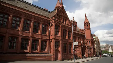 The front of Birmingham Magistrates' Court - a red brick judicial building with two floors of windows and a clock over the main entrance.