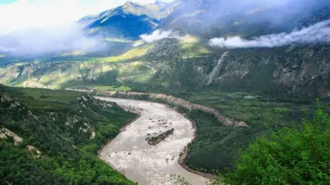 A view of Yarlung Zangbu Grand Canyon showing the eponymous river winding through a deep, wide and verdant canyon.