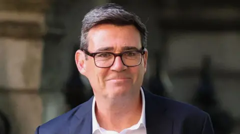 Andy Burnham pictured wearing a white shirt and dark suit